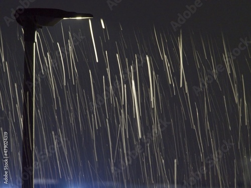 Schneeflocken im Wind vor Straßenlampe photo