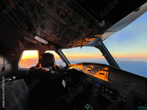 Fototapeta Naklejka Na Ścianę i Meble -  Pilots on the cockpit of an airliner flying at sunrise