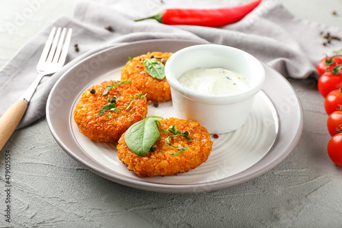 Plate with tasty lentil cutlets and sauce on grey background