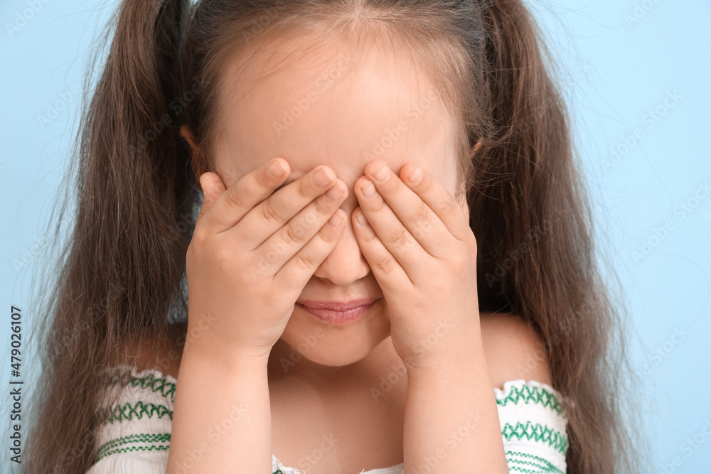 Little girl with ponytails closing eyes on blue background, closeup Little girl with ponytails closing eyes on blue background, closeup