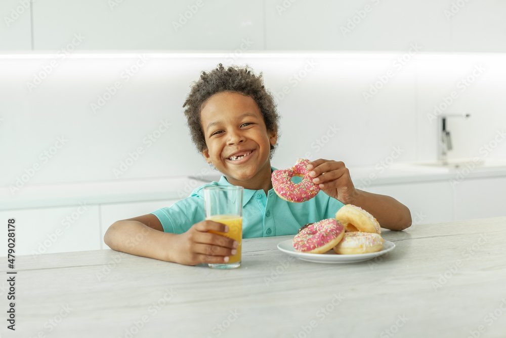 Laughing kid boy with orange juice and donuts Laughing kid boy with orange juice and donuts