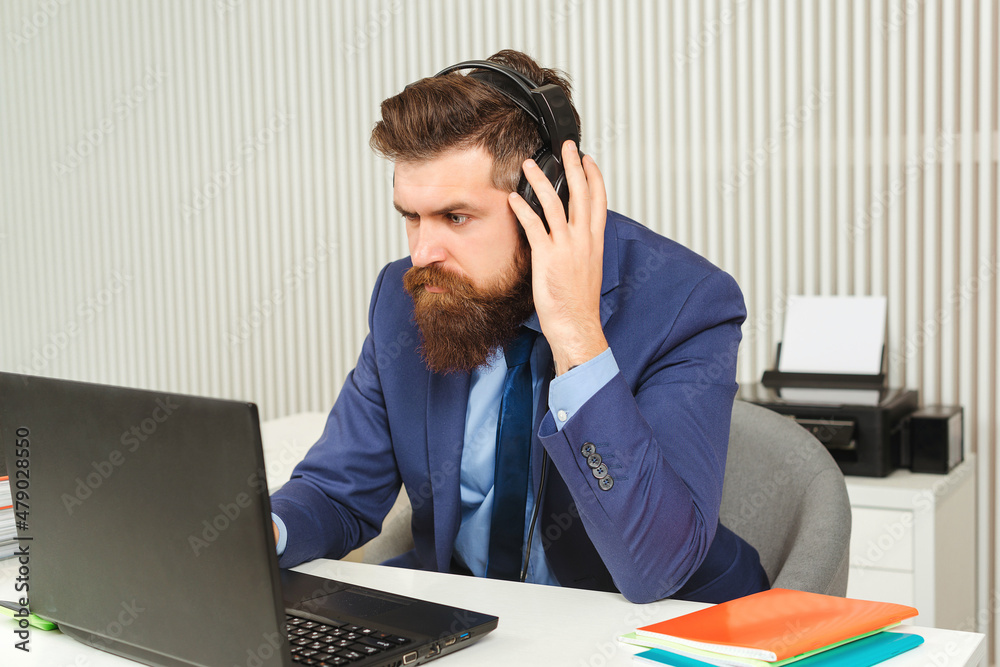 Serious man working on laptop at workplace. Bearded businessman wearing suit. Serious man working on laptop at workplace. Bearded businessman wearing suit.