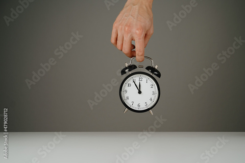 Hand holding black alarm clock