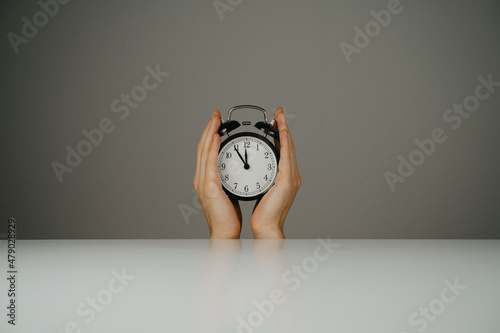 Two hands holding black clock