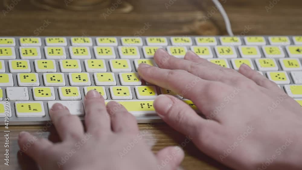 Close-up of a computer keyboard with braille. A blind girl is typing words on the buttons with her hands. Technological device for visually impaired people. Tactilely touches bumps on the keys