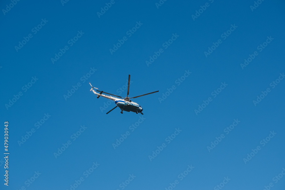 Modern helicopter flying in the blue sky.Flying transport helicopter.The aircraft, the big helicopter at competitions makes flight at low height. Modern helicopter flying in the blue sky.Flying transport helicopter.The aircraft, the big helicopter at competitions makes flight at low height.