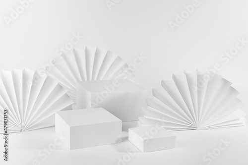 White abstract stage with set of three podiums mockup for presentation of cosmetic produce  advertising  design in geometric minimal style with light asian paper fans  arch  side view  corner  3d.