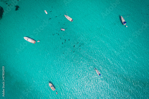 Aerial view of many yachts and sailboats in turquoise water in Mediterranean Sea next to Sardinia island, La Pelosa beach