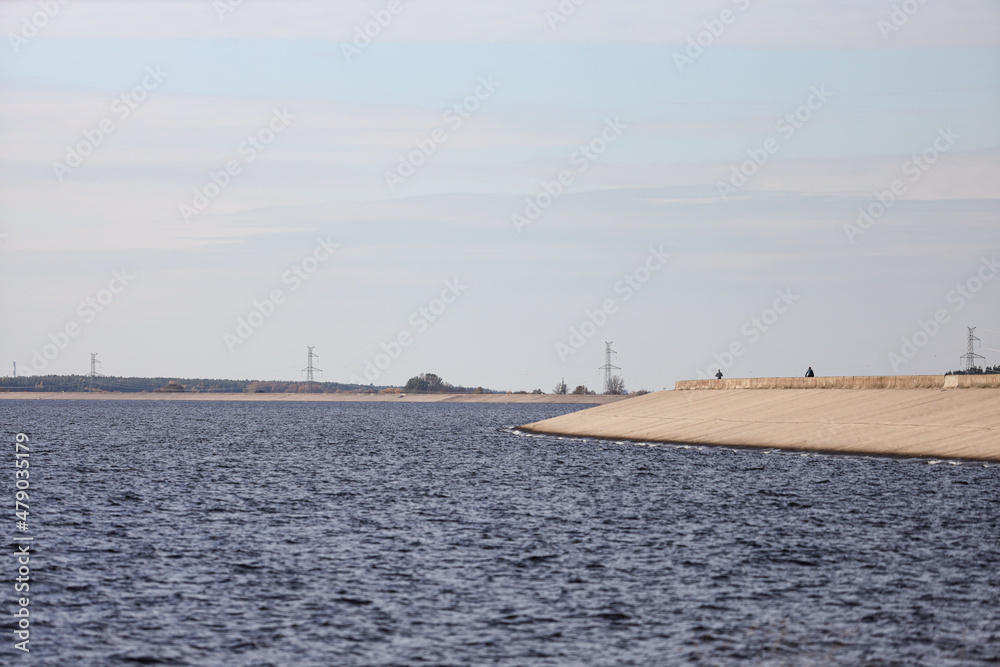 Large river view with large seawall, dam in background.