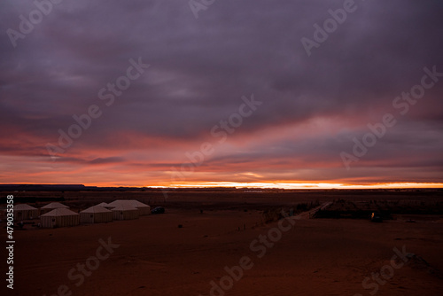 Luxury glamping camp on sand in sahara desert against dramatic sky during sunset, Campsite over sand dunes in desert © Aerial Film Studio