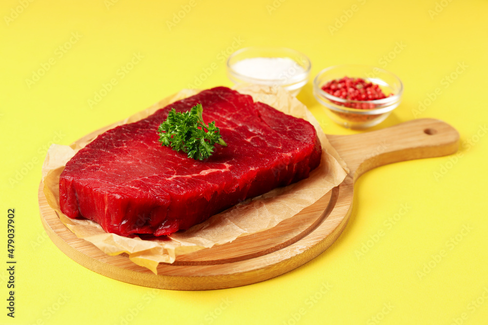 Concept of cooking with raw beef steak on yellow background Concept of cooking with raw beef steak on yellow background