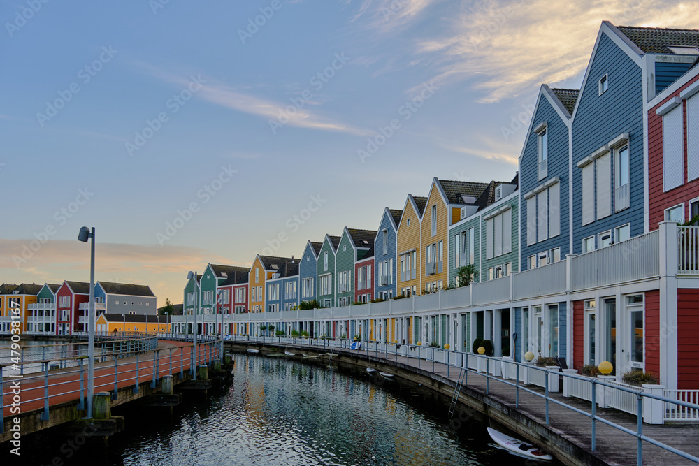 Row of colourful wooden newly built Dutch houses surrounded by water of lake De Rietplas in Houten in the Netherlands.