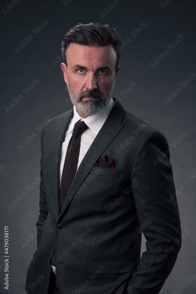 Portrait of a stylish elegant senior businessman with a beard and casual business clothes in photo studio isolated on dark background gesturing with hands Portrait of a stylish elegant senior businessman with a beard and casual business clothes in photo studio isolated on dark background gesturing with hands