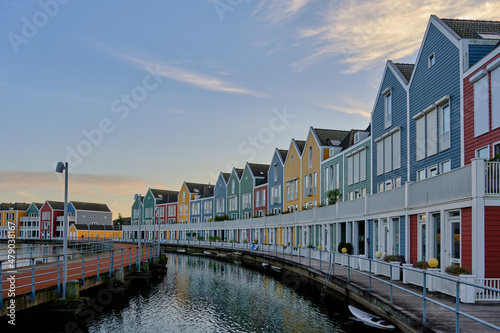 Row of colourful wooden newly built Dutch houses surrounded by water of lake De Rietplas in Houten in the Netherlands. © Nigel Wiggins