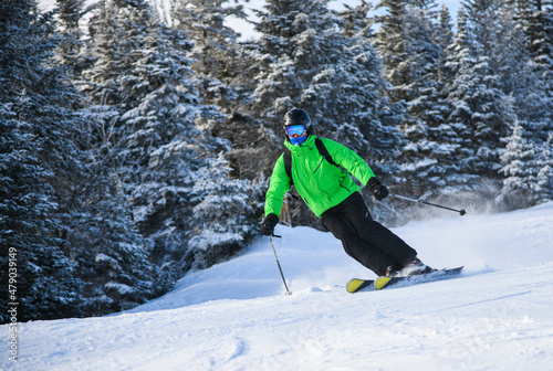 Male skier in bright outfit skiing downhill on fresh powder snow. Motion photo.