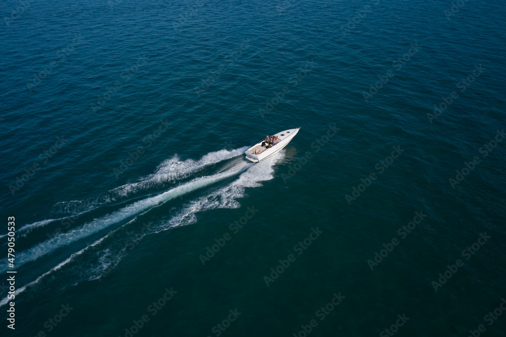 Boat on the water top view. White boat with people on dark blue water aerial view. People in a boat in motion top view. Boat on the water top view. White boat with people on dark blue water aerial view. People in a boat in motion top view.