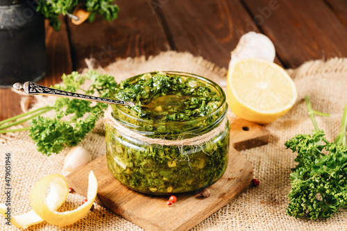 Traditional chimichurri sauce with parsley, garlic, pepper, lemon, vinegar on a wooden table. photo