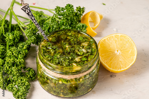 A can of healthy chimichurri sauce based on parsley and olive oil, close-up, on a white table.