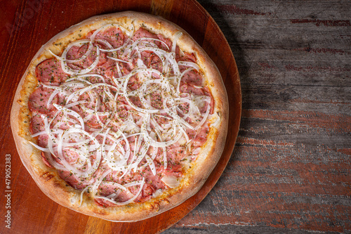 pepperoni pizza on wooden background. Brazilian pizza called pizza de calabresa. top view photo