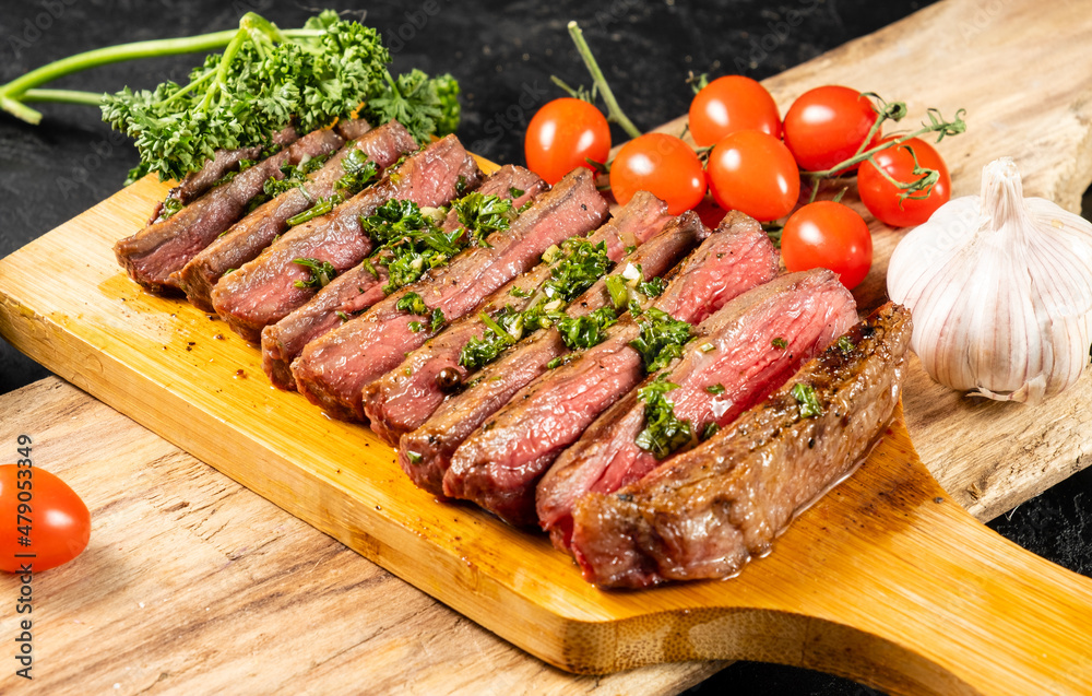 Grilled beef steak sliced into pieces served on a wooden board. Grilled beef steak sliced into pieces served on a wooden board.