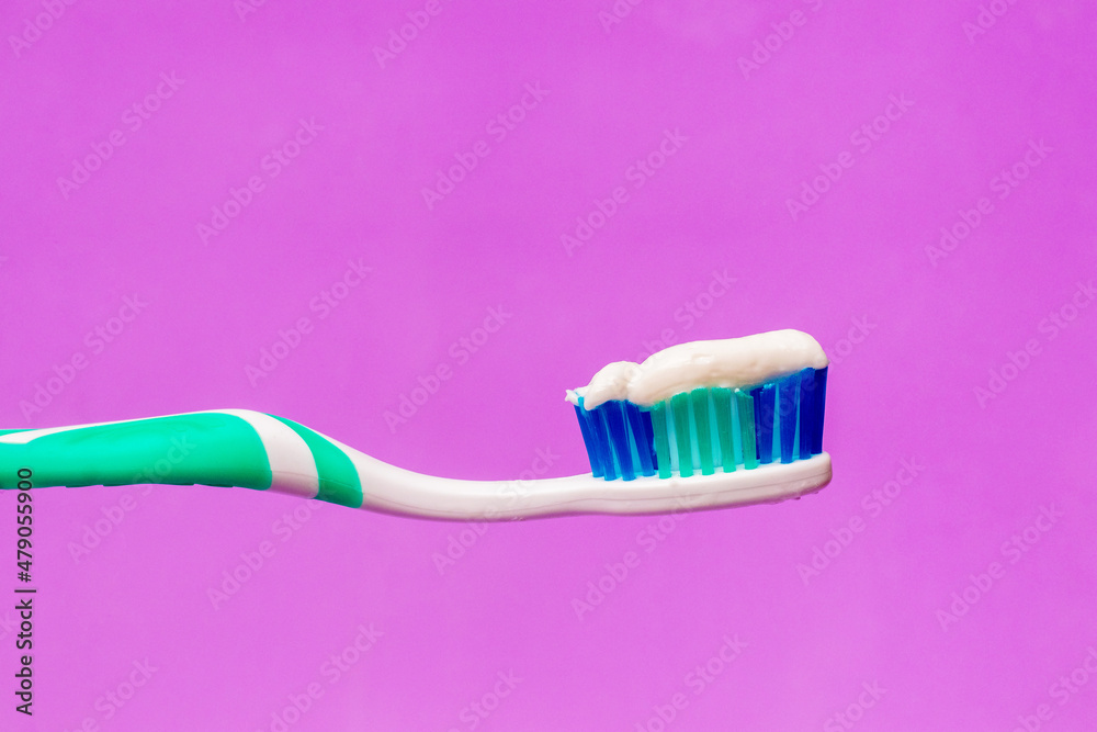 Toothbrush with toothpaste on a purple background, dental care