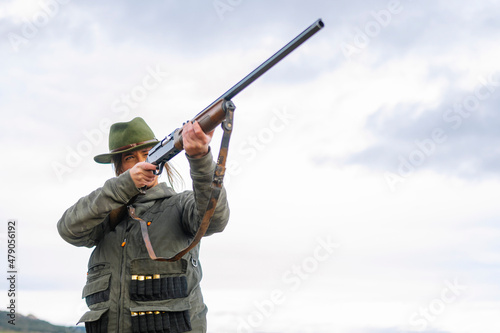 Hunter woman with shotgun hunting in the field.