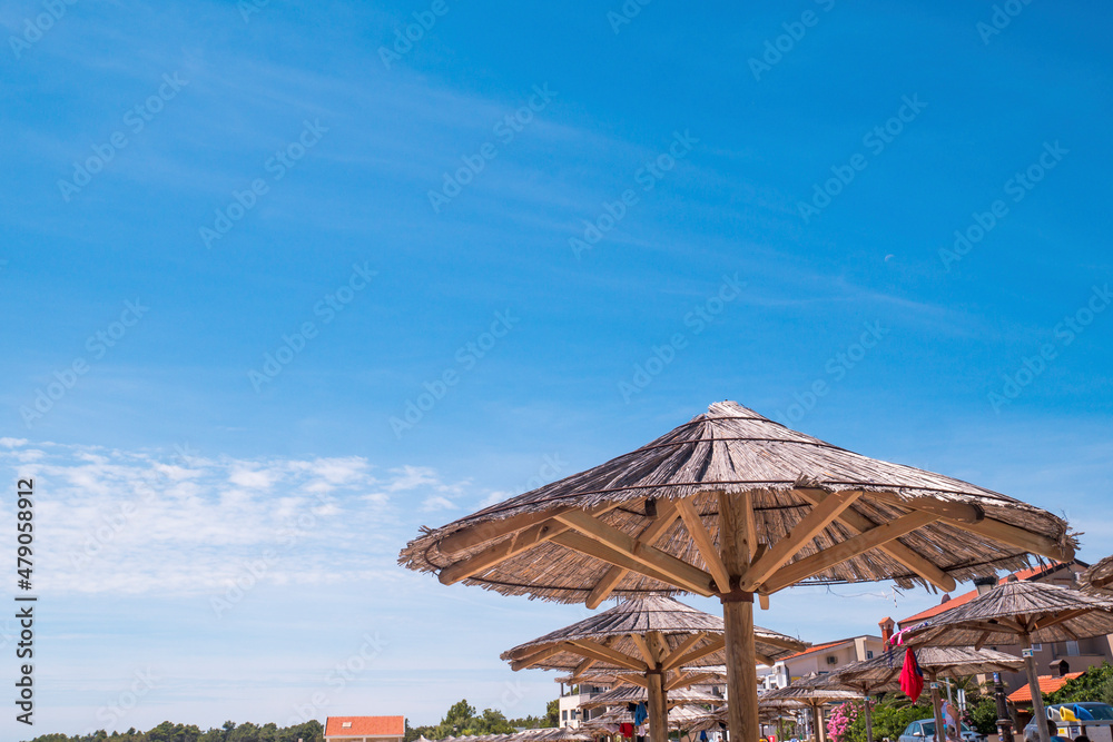 View of the beautiful blue sky and straw beach umbrellas