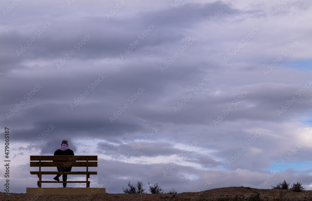 Rear view of man sitting on bench against cloudy Sky. Almeria, Spain