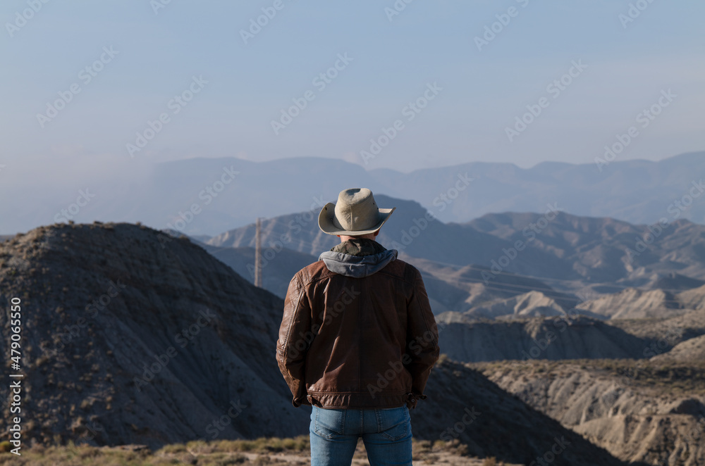 Rear view of adult man in cowboy hat looking at view of Tabernas Desert, Almeria, Spain