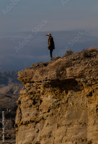 Adult man in cowboy hat standing on top of cliff in Tabernas Desert, Almeria, Spain