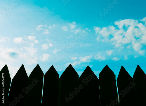 blue sky  clouds and a picket fence 