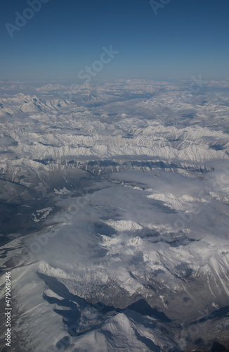 Aerial view of snow covered rocky mountains in Canada or Canadian Rockies as seen from window seat of airplane while in flight travelling on plane from Alberta  Canada to British Columbia 