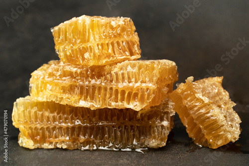 Golden Bee honeycomb wax with honey on black background. Honey dripping from honey comb close up.