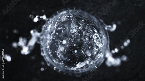 Super Slow Motion Shot of Ice Cube Falling into Glass With Vodka on Dark Background at 1000 fps. photo