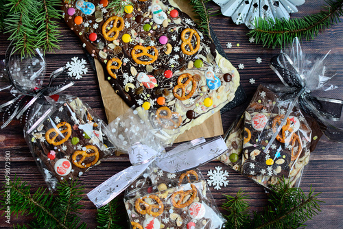 New Year's gift idea. Homemade chocolate with nuts, salted pretzels, nuts and sprinkles on a dark wooden background