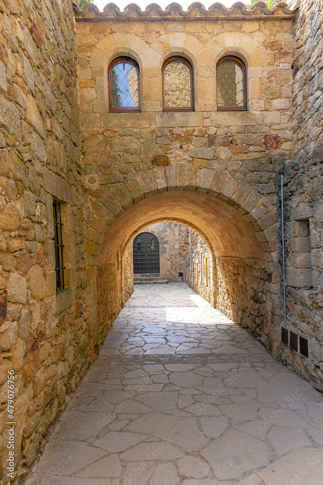 Pals, street with stone buildings, arch across the street with reflection in the windows, in the old town of Pals, catalonia, Girona, northeastern spain.