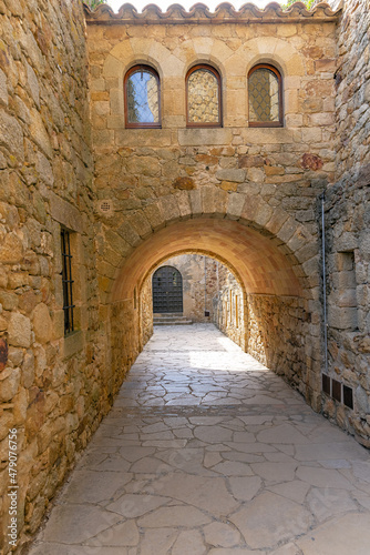 Pals, street with stone buildings, arch across the street with reflection in the windows, in the old town of Pals, catalonia, Girona, northeastern spain.