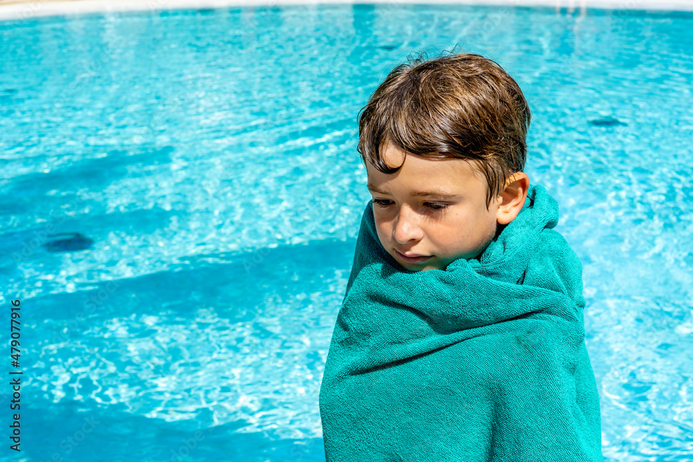 Boy wrapped in towel feeling cold after swimming standing next to pool. High quality photo Stock Photo Adobe Stock