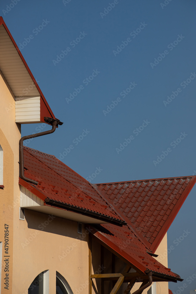 The roof of the house is made of red metal tiles, a beautiful large chimney