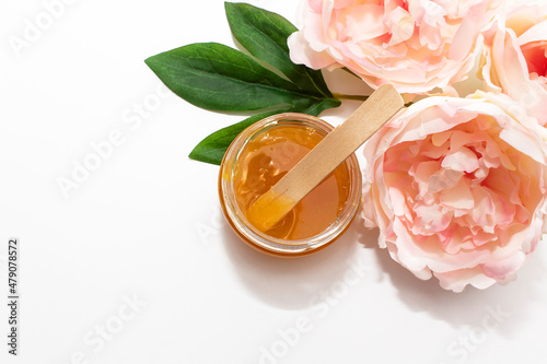 Konstfotografi Liquid sugar paste for hair removal in a bowl with peony flower on white background