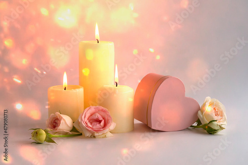 blurred bokeh valentine s day background with candle lights roses and a pink heart-shaped box. 