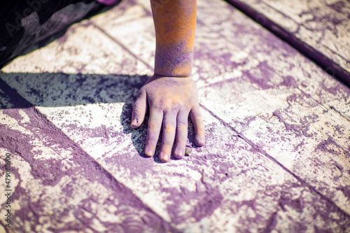 a little, cheerful girl at the Holi festival, in a purple T-shirt, stained with paint