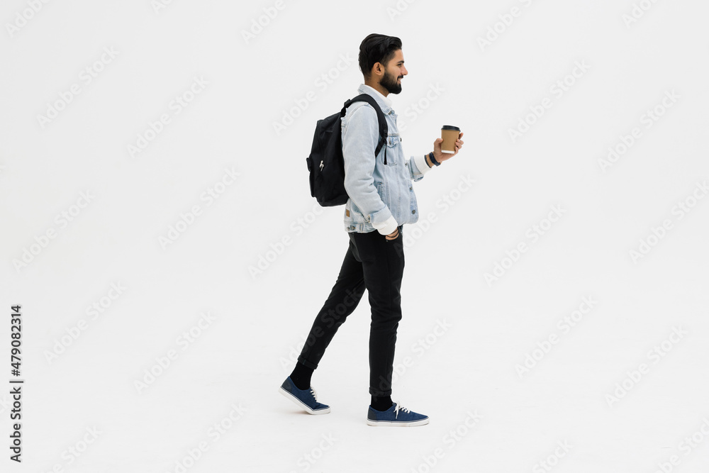 Young handsome indian man with backpack holding coffee cup isolated on gray background. Young handsome indian man with backpack holding coffee cup isolated on gray background.