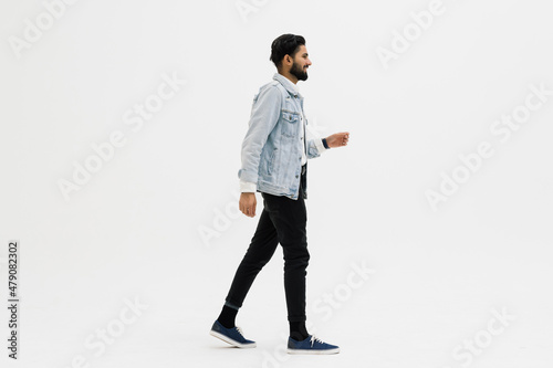 Full length side shot of handsome beard man smiling and walking, isolated on white background