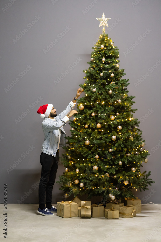 Young indian man decorating christmas tree in office Young indian man decorating christmas tree in office