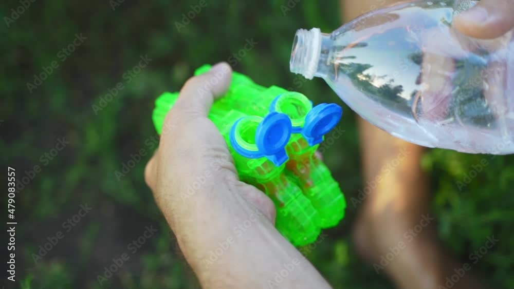 Water Getting Shot Kids pours water from a bottle into a water gun. Water pistol battle in ...