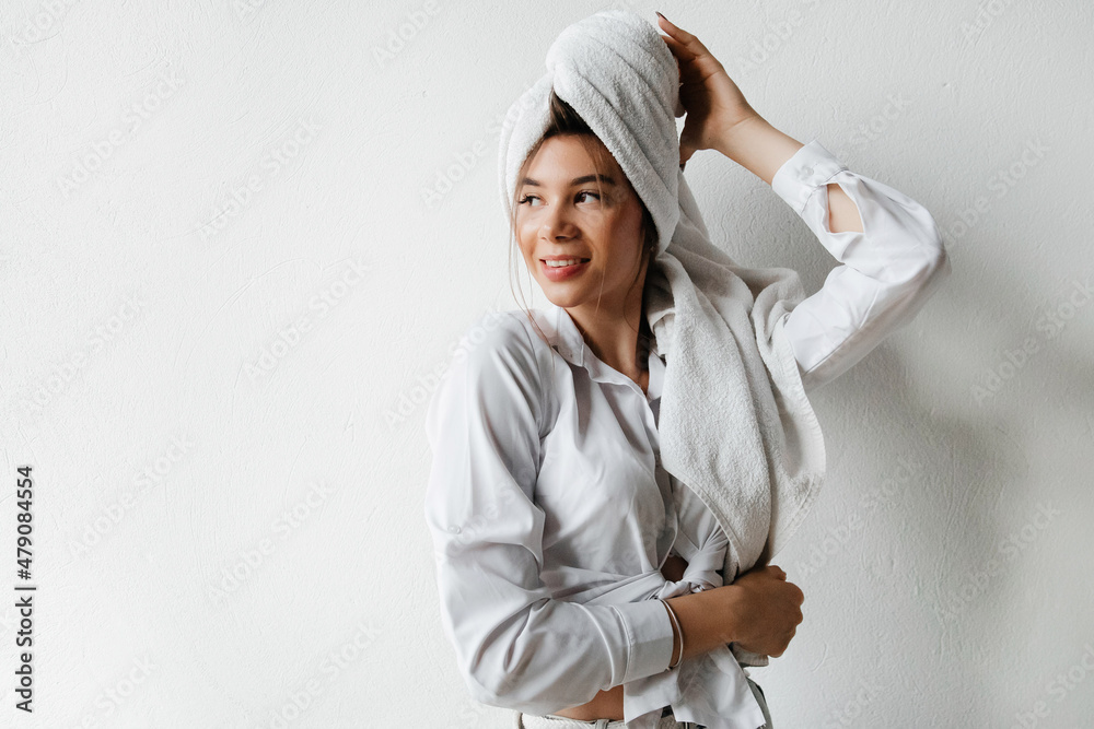 Young woman with a towel on her head is getting ready for university. Young woman with hair wrapped in towel indoors, looking too the side