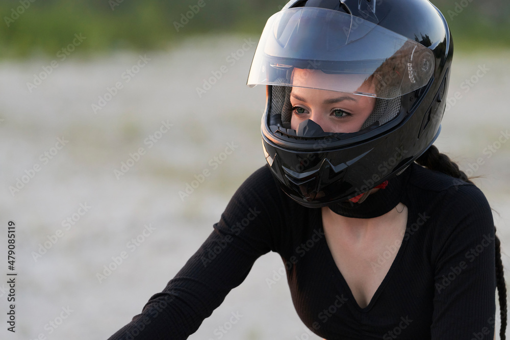 Portrait of a pretty biker girl in a protective helmet in nature. Selective focus. Copy space. Portrait of a pretty biker girl in a protective helmet in nature. Selective focus. Copy space.