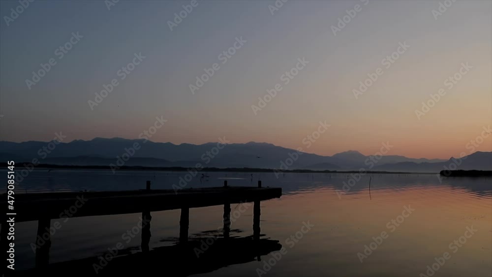 Elderly couple walking hand in hand on pier at sunset Elderly couple walking hand in hand on pier at sunset