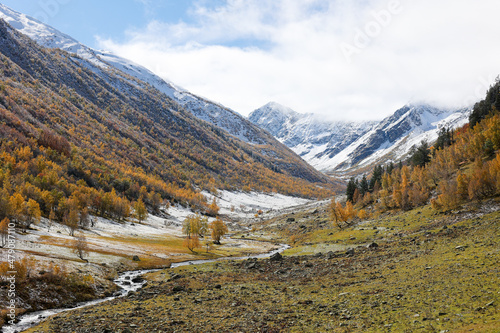 Fantastic mountain landscape. River valley in the mountains in golden autumn. Sunny day. Without people. First snow.